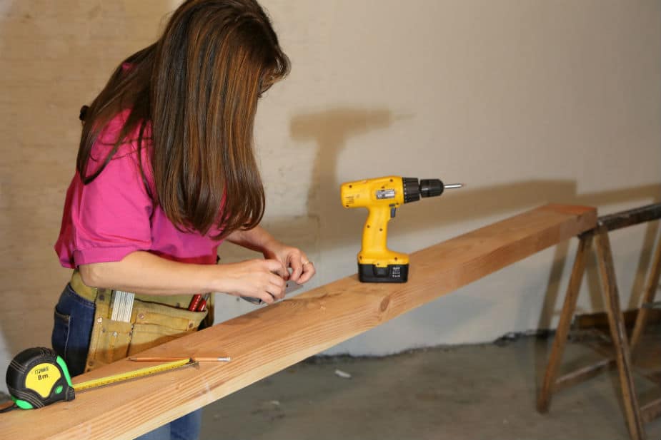 Yellow portable drill with women in a garage workshop. Large image.