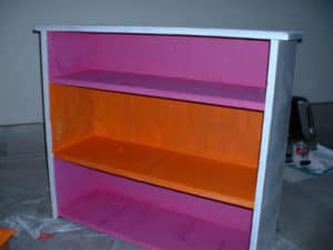 Wooden bookcase with orange and magenta paint