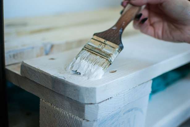 Woman holding paintbrush with primer - Can you sand MDF