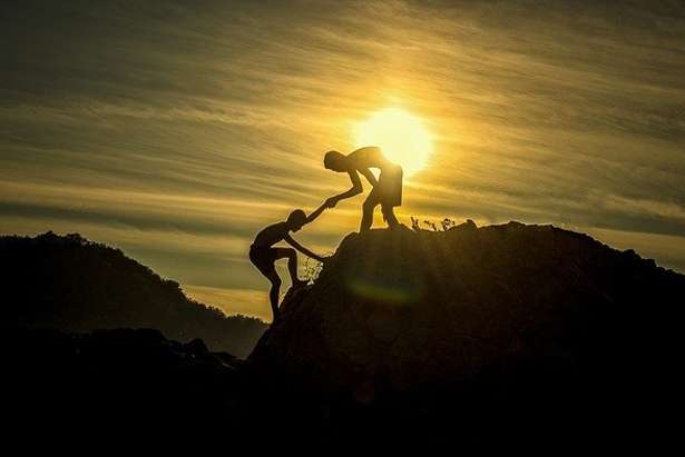 Man helping another to climb mountain