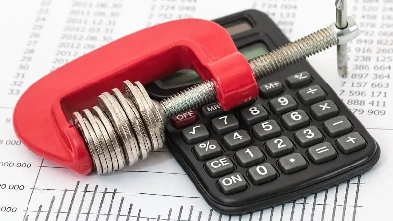 Red clamp squeezing coins and calculator - Can be learned at home on a budget - Wood is Good - 10 Reasons To Get Into Woodworking