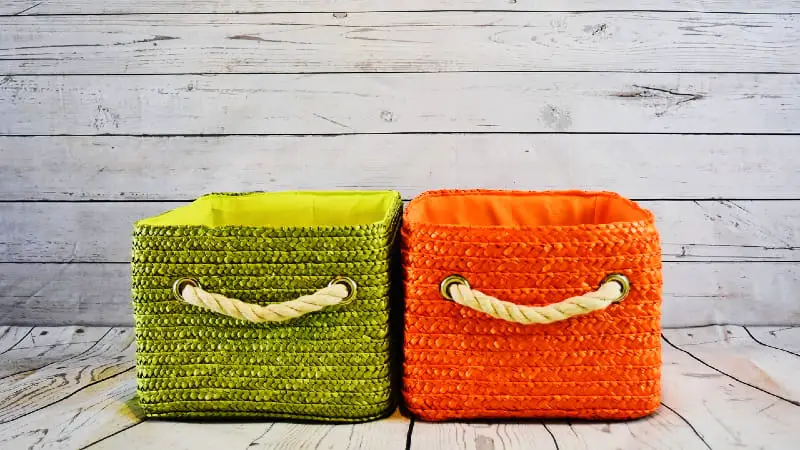 Two rectangular storage baskets with rope handles. The basket on the left is green, and the one on the right is orange.