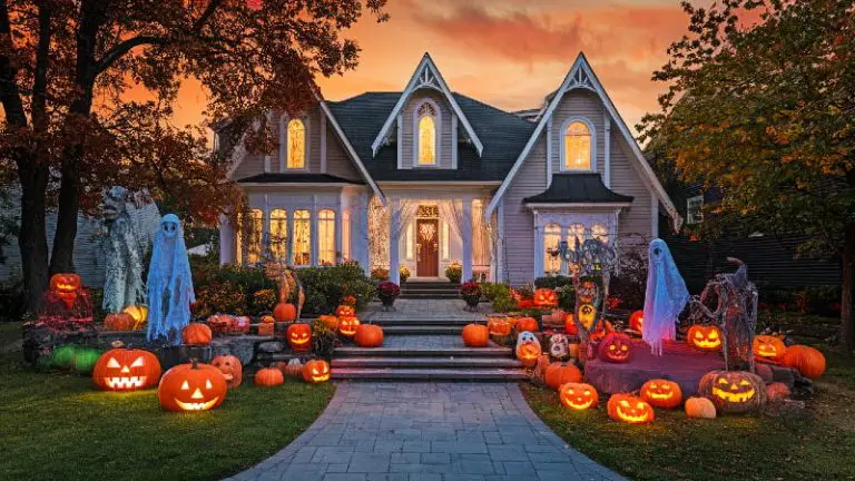 A sprawling front yard dramatically decorated with a mix of scary and creative Halloween outdoor decorations, illuminated by eerie colored lights at dusk.